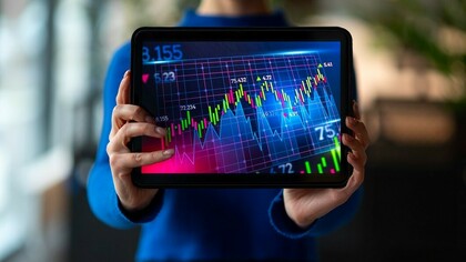 A person in an office analyzing and reviewing financial graphs for market insights