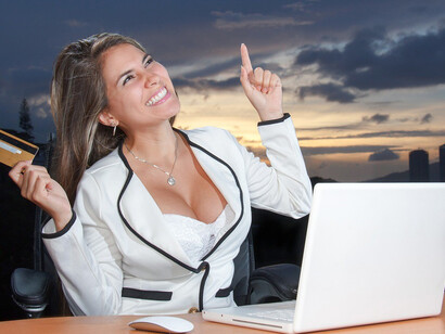 The woman's eyes light up with excitement as she navigates her favorite online store, holding a credit card in her hand ready to make a purchase