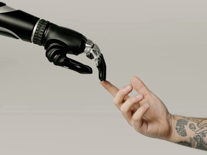 Mão humana interage com mão robótica. O lendário Teste de Turing tem como objetivo que uma máquina se envolva em conversas de forma tão convincente que um juiz não consiga dizer se é um humano ou uma máquina. Atualmente, estamos muito longe de atingir o nível de algoritmos de IA ou poder de processamento computacional necessário para que isso ocorra, mas a Lei de Moore indica que eventualmente chegaremos lá