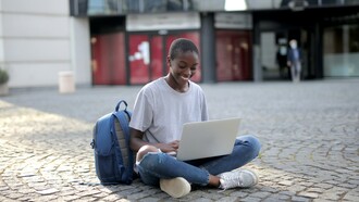 Estudante sentada com computador na rua