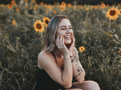 A young woman in a sunflower field, smiling