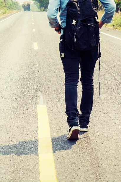 Vista posteriore di donna che cammina lungo la strada: "A noi claudicanti camminatori del XXI secolo non resta che metterci in cammino per cercare di comprendere il metodo e la sua negazione, non ci resta che andare"