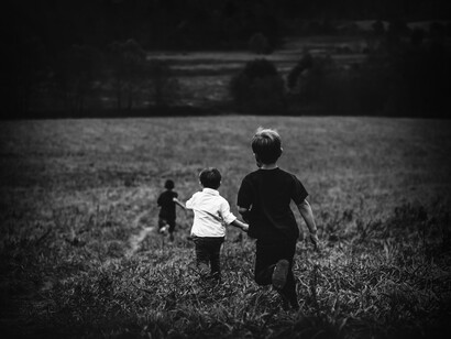 Amigos de infancia corriendo en medio de una pradera
