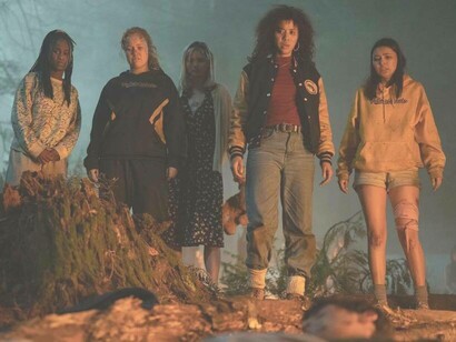 Members from the cast of Yellowjackets exploring the wooded area and look horrified