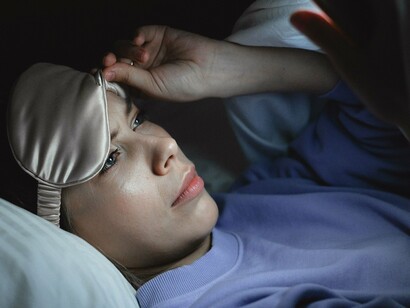 Deitada na cama e já preparada para dormir, a mulher ainda mantém os olhos voltados para o celular. O hábito de permanecer conectado até os últimos momentos do dia pode dificultar a transição entre a agitação das telas e o descanso