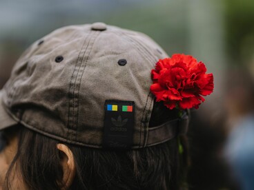 Jovem com uma rosa presa ao boné observa o ambiente à sua frente. O artigo aborda os desafios enfrentados por quem procura construir o futuro em um contexto de crescente incerteza social e económica