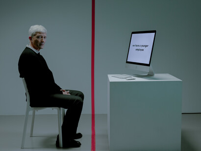 A man stares sadly while a computer displays a rejection message