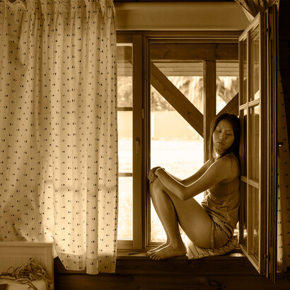 Mulher em janela. A vida transformou-se numa obsessão entre paixões e dor a correr no sangue, rio de cicatrizes com a felicidade a desvanecer-se de noite