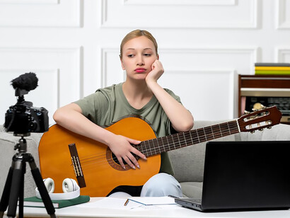 Explore the world of e-learning with a charming image of a young, cute, and beautiful girl delivering guitar classes from the comfort of her home, showcasing the convenience and appeal of remote education