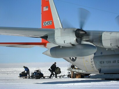 Suprimentos são carregados de um trenó para um LC-130 Hercules em um posto remoto de pesquisa na Groenlândia. A operação evidencia a complexa infraestrutura necessária para manter atividades humanas em áreas isoladas do Ártico