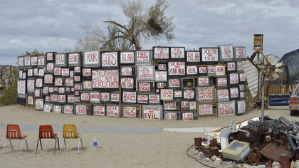 Ell muro de la verdad en Slab City; televisores con palabras de noticias falsas y mensajes de propaganda frente a deshechos electrónicos