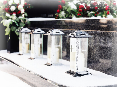 Lighting candles is also a tradition to honor our loved ones who have passed on; here are four in a row in a snow-covered cemetary