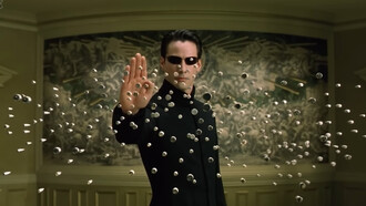 Neo suspending hundreds of bullets in midair with a raised hand, representing one of The Matrix Reloaded's defining moments as he surpasses the limits of the simulated world