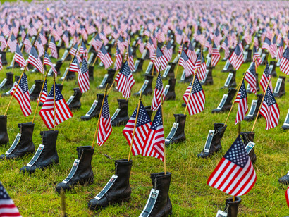Fallen soldier's graves with a military boot as a headstone marker, and a American flag