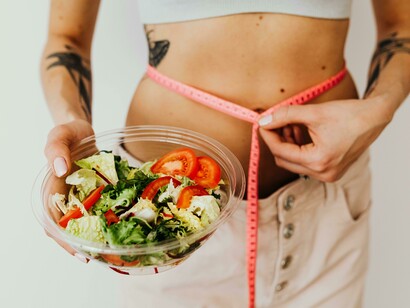 A toned woman enjoying a vegetable salad as part of her weight-loss journey
