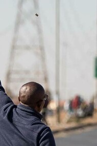 A South African in the middle of the road raising a gun to the sky crying out for justice