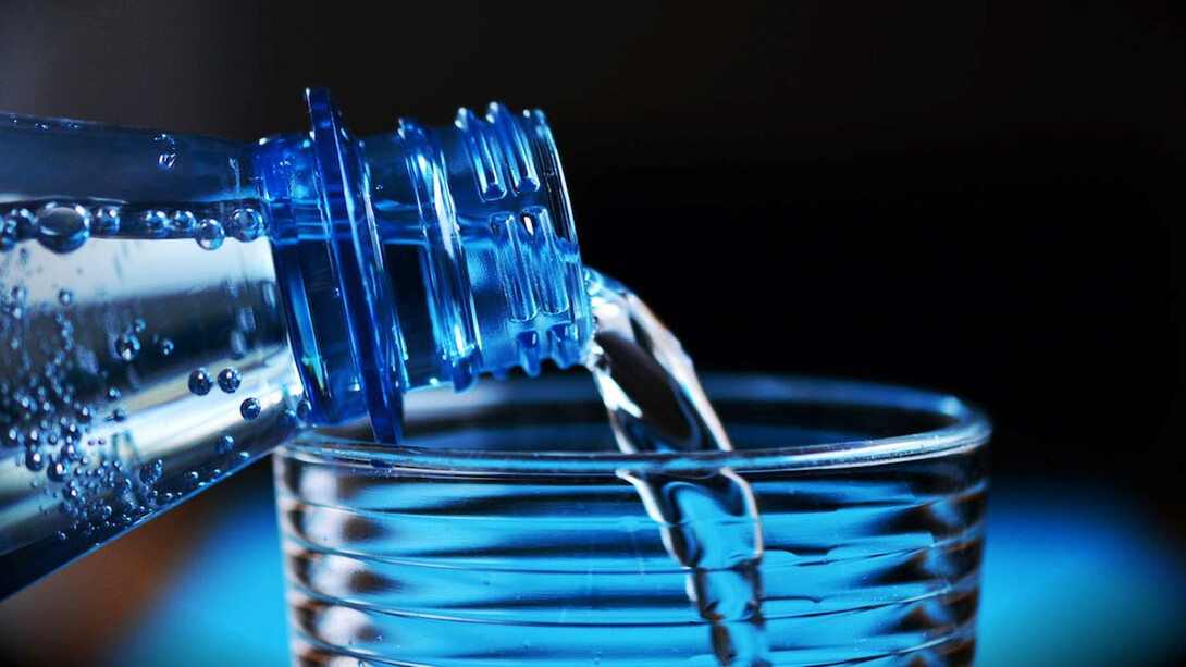 Clear glass and a water bottle with a mesmerizing visual as water gracefully flows from the bottle into the waiting glass