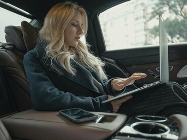 A woman working on a laptop while traveling, representing the expectation to remain productive wherever we are