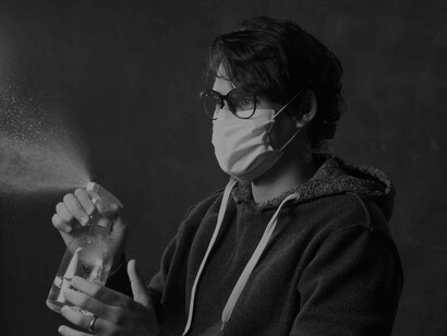 A masked young man spraying disinfectant as is the norm in today's coronavirus pandemic situation