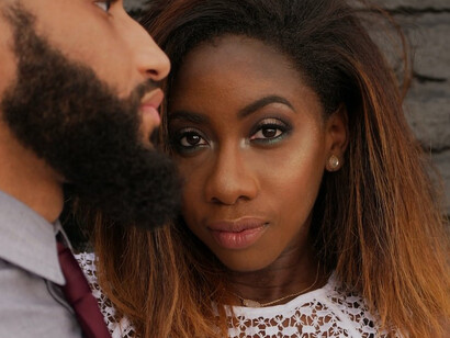 A man tenderly embracing a woman against a backdrop of a gray wall