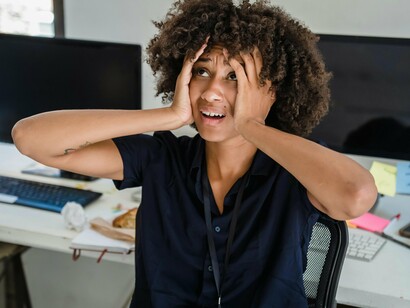 Mulher sobrecarregada de trabalho. É importante estabelecer metas realistas e proporcionar recursos adequados para que os funcionários possam desempenhar suas funções de maneira eficiente e sem sobrecarga