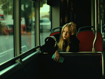 A blonde woman commuting alone by bus
