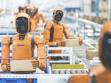 Humanoid robot performing package sorting and material handling tasks in an automated warehouse, demonstrating next-generation AI-driven logistics operations