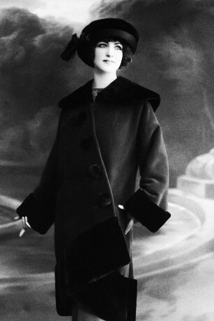 A black and white photo of a woman wearing a coat and hat, showcasing 1920s vintage fashion that epitomizes old money style and generational wealth