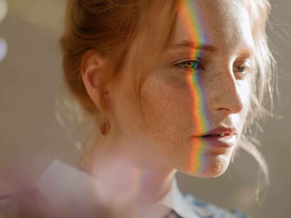 A woman reflecting as a rainbow nestles on her face