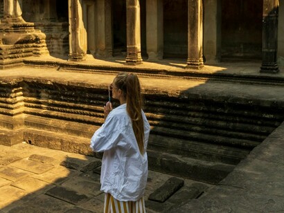 Mulher no pátio de Angkor Wat, Siem Reap, Camboja. Confesso que fui para essa viagem — e, consequentemente, para esse destino — sem saber exatamente o que encontraria. Não costumo pesquisar nada sobre os meus destinos de viagem, além do necessário, pois gosto muito de ser surpreendida pelo que irei encontrar. Em um dos dias em que contemplávamos um dos diversos templos do cronograma que tínhamos, fui tomada por uma inquietude. Eu tinha sede de conhecimento, eu queria saber mais, queria poder acessar as outras camadas de uma cultura tão distante da minha