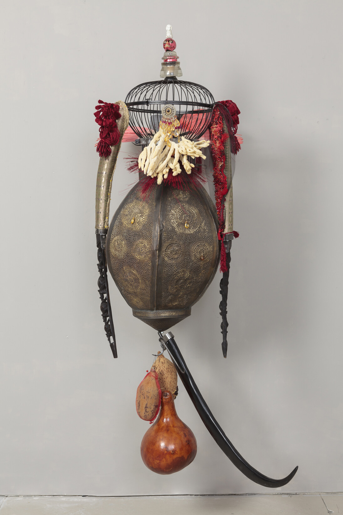 Rina Banerjee, Soldier : overseas and out of place his species seeded dead to grow as common place, bore beautiful flowers of wound, carnage discovered a resin sticky like sweat. He had courage and loyalty when everyone wept and came home emptied while we slept, 2014. Brass Lantern, acrylic horn, wire cage, wood carved elephant souveniers, gourds, arm forms, wedding sari textiles, red skull and mushroom, natural sea sponge. Silk jewelry ties, steel, 213,4 x 55,9 cm, Courtesy of the artist and Galerie Nathalie Obadia, Paris/Bruxelles