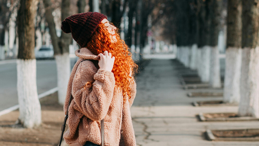 Garota respira profundamente a brisa da manhã gelada que atravessa seu caso em dia frio