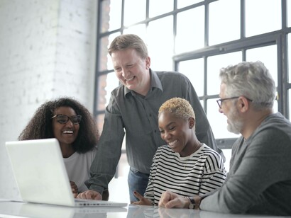 A smiling group of friends at work are going over their latest project