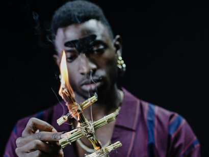 A black man setting a wooden idol on fire