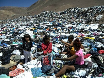 Crianças em meio a lixão têxtil no Deserto do Atacama, Chile. A indústria da moda é responsável por cerca de 4% a 8% das emissões de carbono na atmosfera, o que gera uma série de alterações climáticas no planeta como a poluição do ar e o desequilíbrio da temperatura média da Terra 