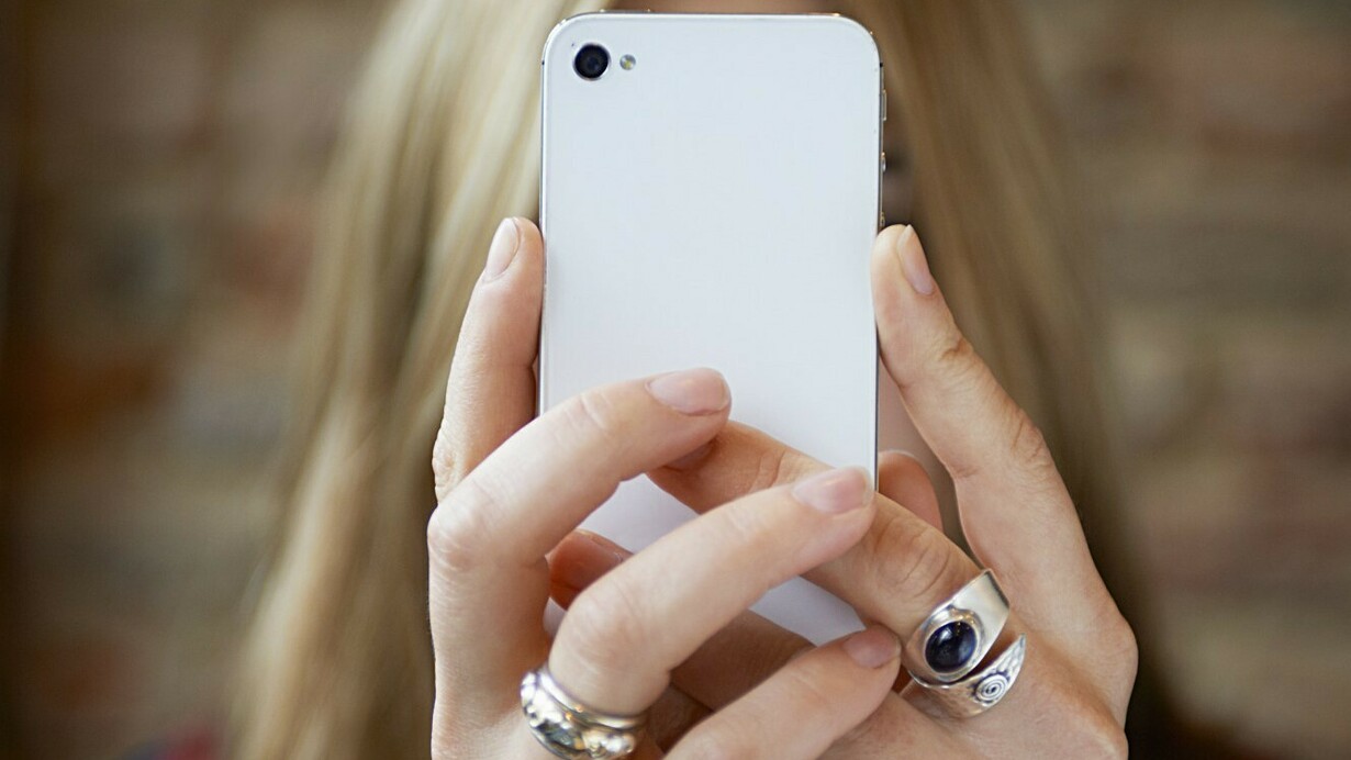 Una chica absorta mirando su teléfono móvil