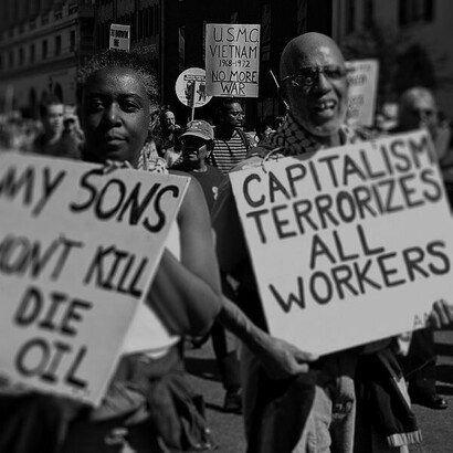 Manifestante sostiene un cartel que versa "el capitalismo aterroriza a todos los trabajadores" durante una protesta anti bélica