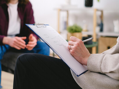 A psychologist takes notes during a therapy session focused on mental health