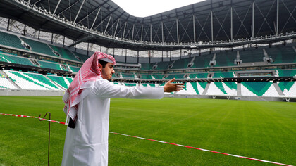 Pessoa de nacionalidade árabe mostra estádio de futebol em Doha, Catar. Foto de Kai Pfaffenbach