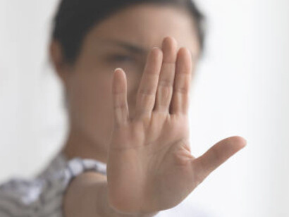 An image capturing an anonymous woman signaling the stop sign with her hand outdoors