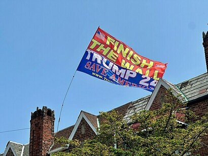 Bandiera che sventola con il messaggio "Finisci il muro, Trump 2024, Salva l'America"