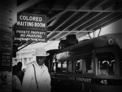 An African American man waiting for a train, in the 'colored' areas near the waiting room for coloreds