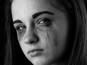 Monochrome image showing a girl in tears, her expression marked by sorrow and despair