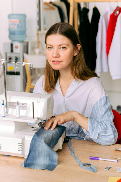 A designer in a fashion studio workspace using a sewing machine and cutting fabric with zero-waste sewing patterns
