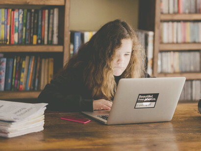 A teenage girl being physically inactive and working on a laptop