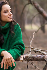 Woman in nature enjoying view, leaning on the tree branch
