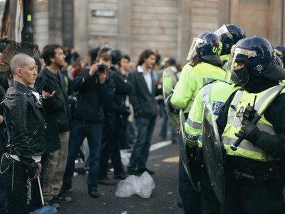Demonstrators face a line of riot police in a tense standoff, representing the right to challenge authority in democratic societies