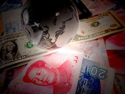 A glass globe placed alongside Chinese yuan currency notes and coins