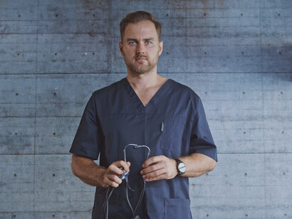 With a stethoscope in hand and a distant gaze, this doctor reflects the weight of responsibility that comes with leading a hospital in crisis