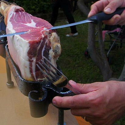 Uomo al taglio di una fetta di prosciutto crudo